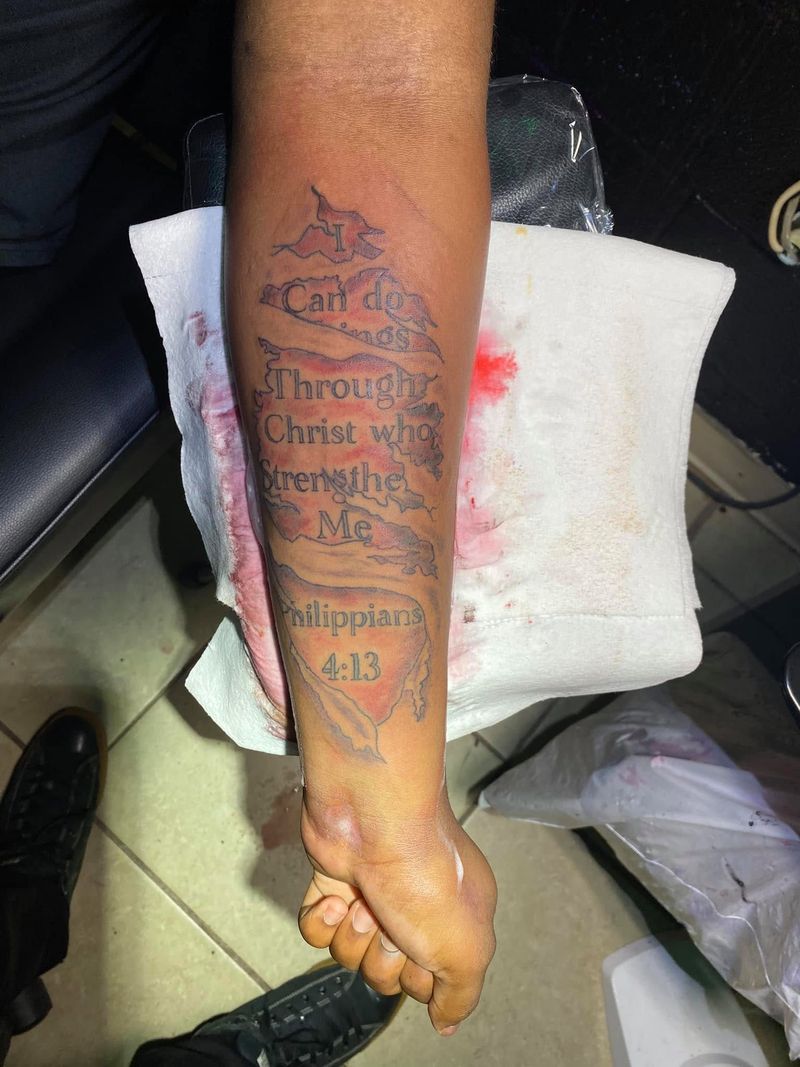 Script tattoo of the verse Philippians 4:13 on a forearm.